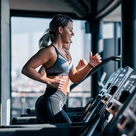 Personas corriendo en caminadoras en un gimnasio